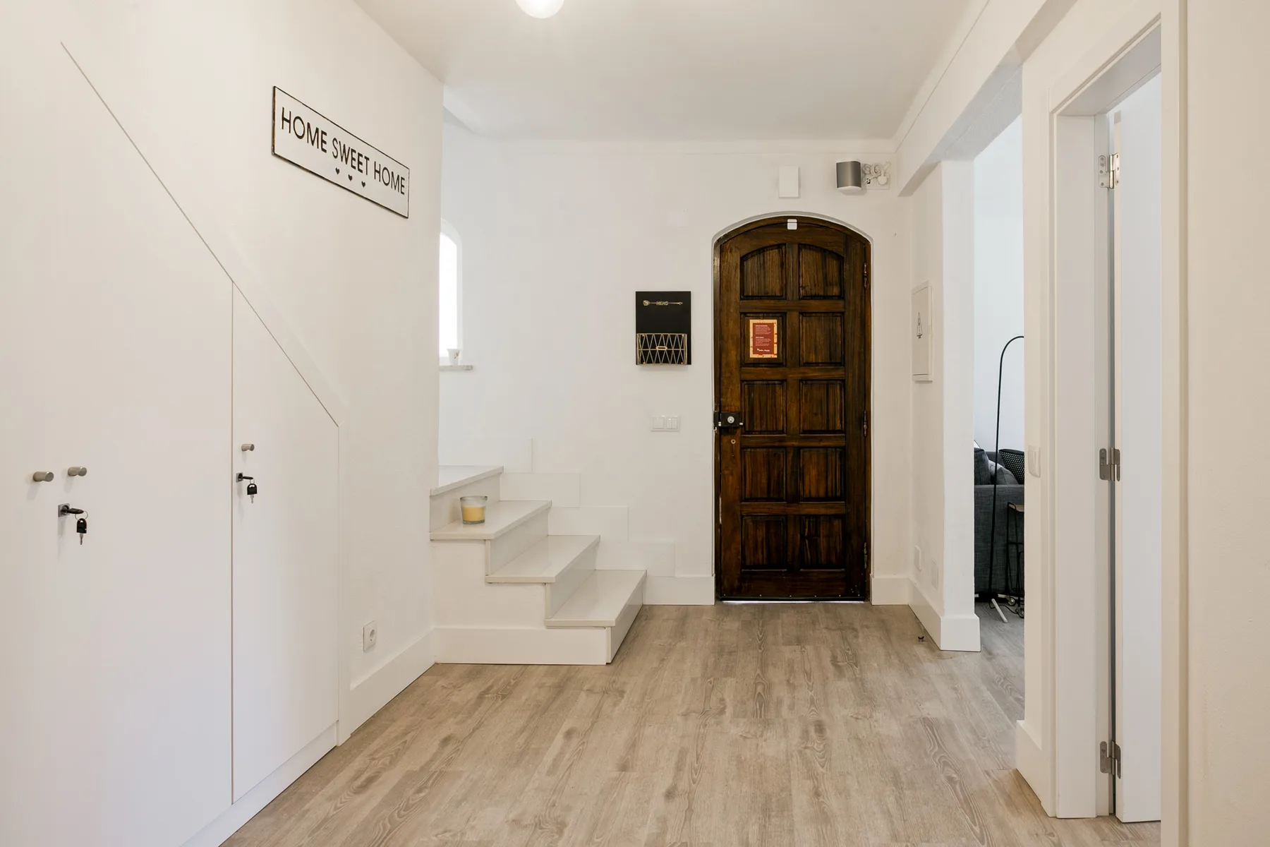 Una entrada luminosa con una puerta de madera oscura y escalones.