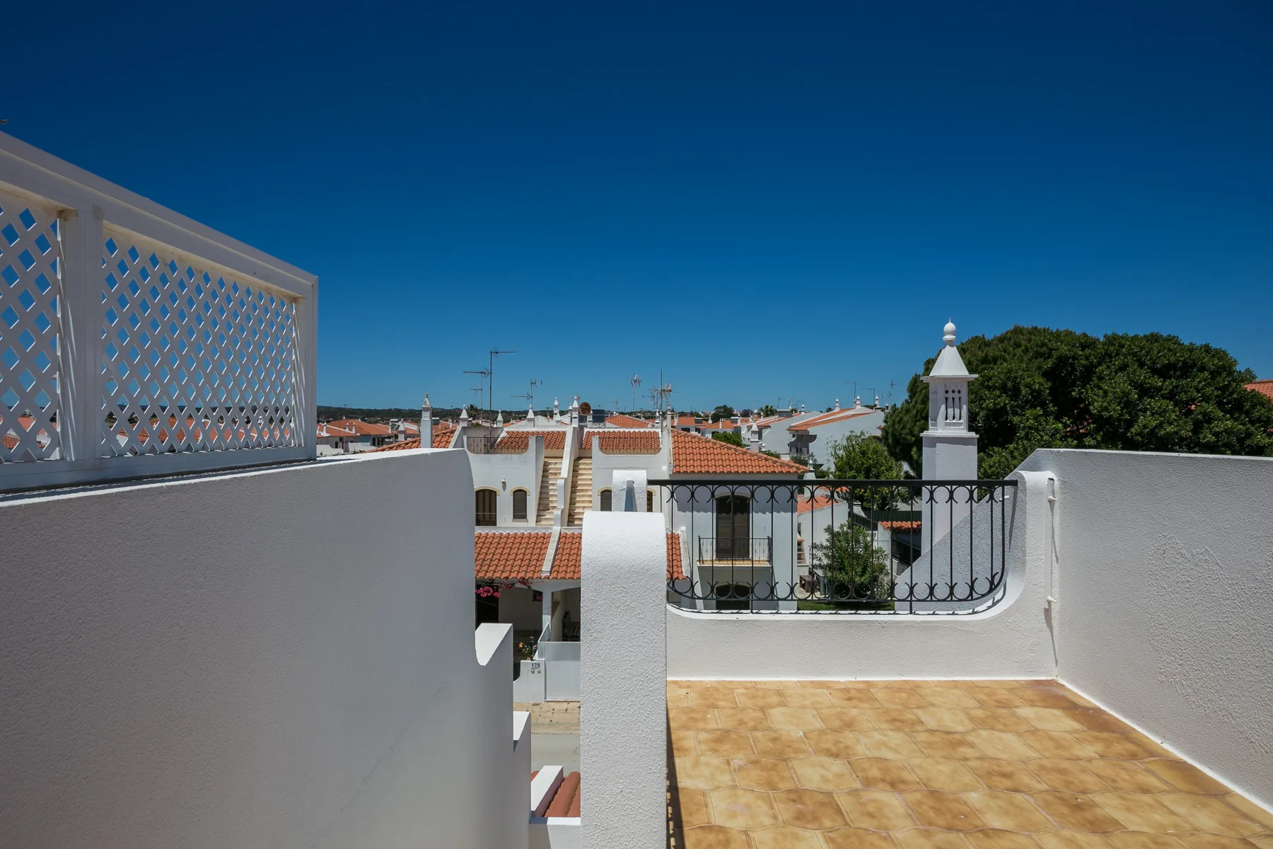 Una terraza en la azotea da a casas cercanas y una pequeña torre.