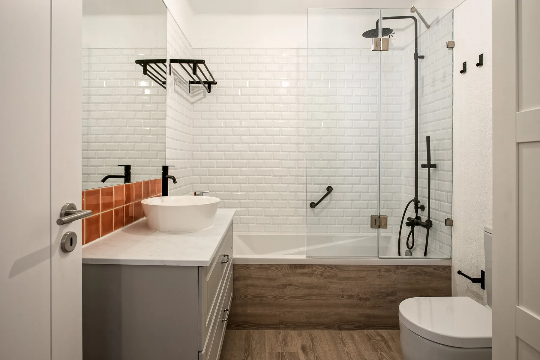 Un baño moderno con lavabo blanco y una ducha con paneles de vidrio.