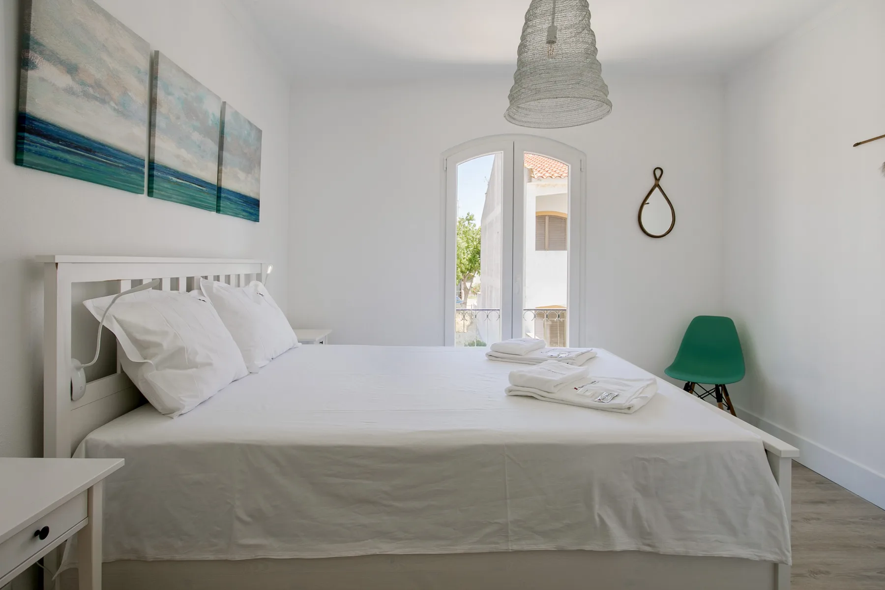 Un dormitorio luminoso con una cama bien hecha y una puerta acristalada.