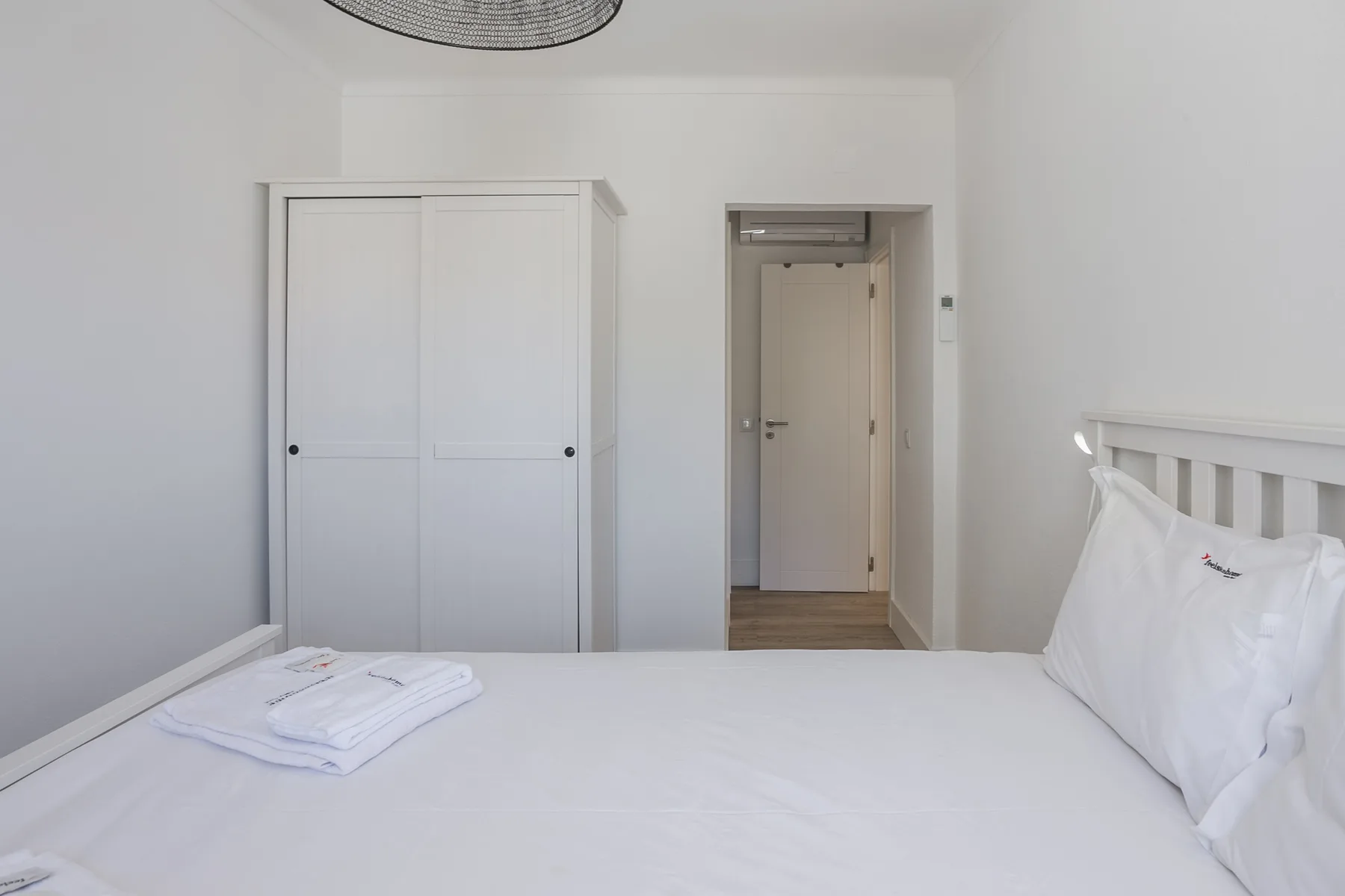 Un dormitorio con una cama bien hecha y una puerta.