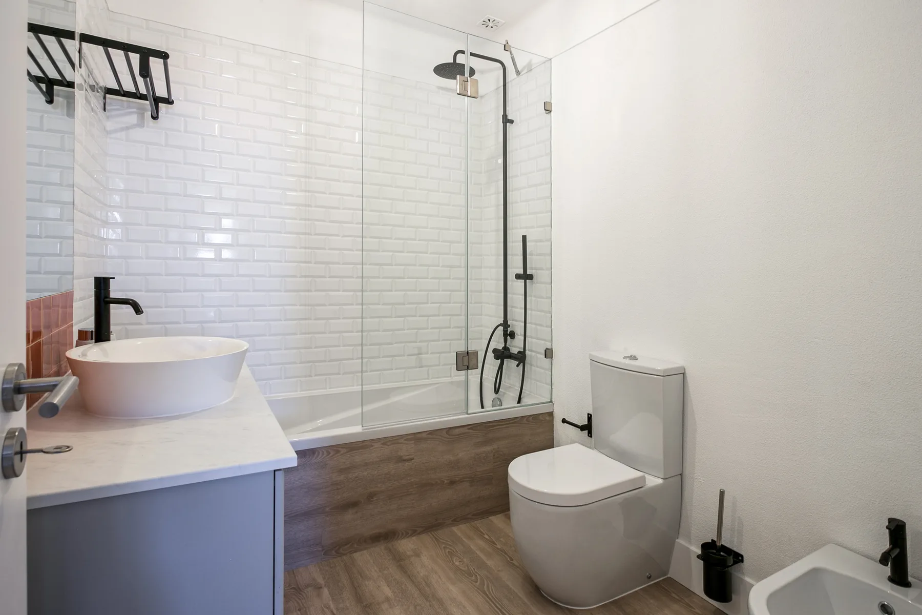 Un baño luminoso con lavabo, inodoro y ducha de vidrio.