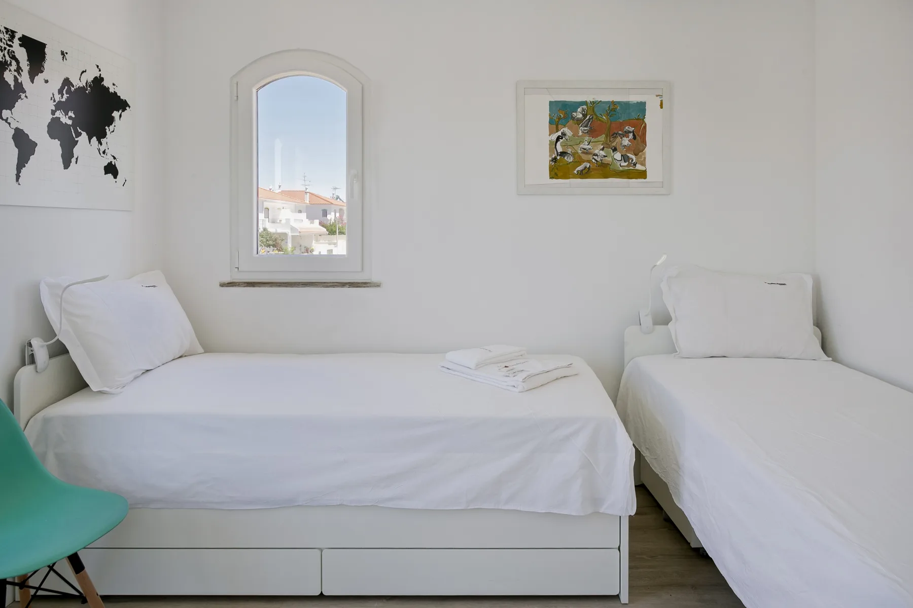 Un dormitorio luminoso con dos camas individuales y cuadros en la pared.