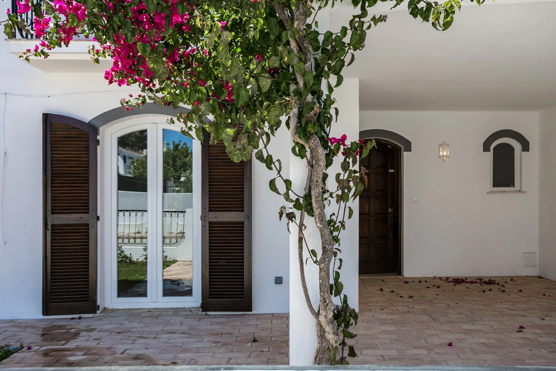 Un patio cubierto con puertas arqueadas y enredaderas floridas.