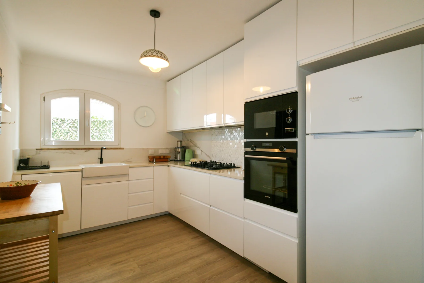 Una cocina luminosa con gabinetes blancos, una estufa y un horno.