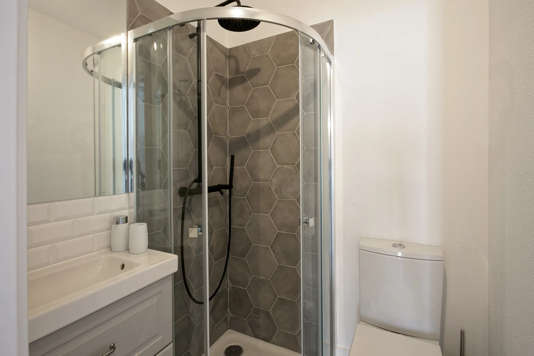 Un baño con una ducha de vidrio curvada y un lavabo.