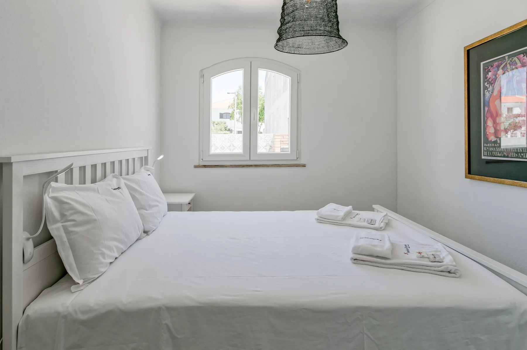 Un dormitorio luminoso con una cama hecha y una ventana.