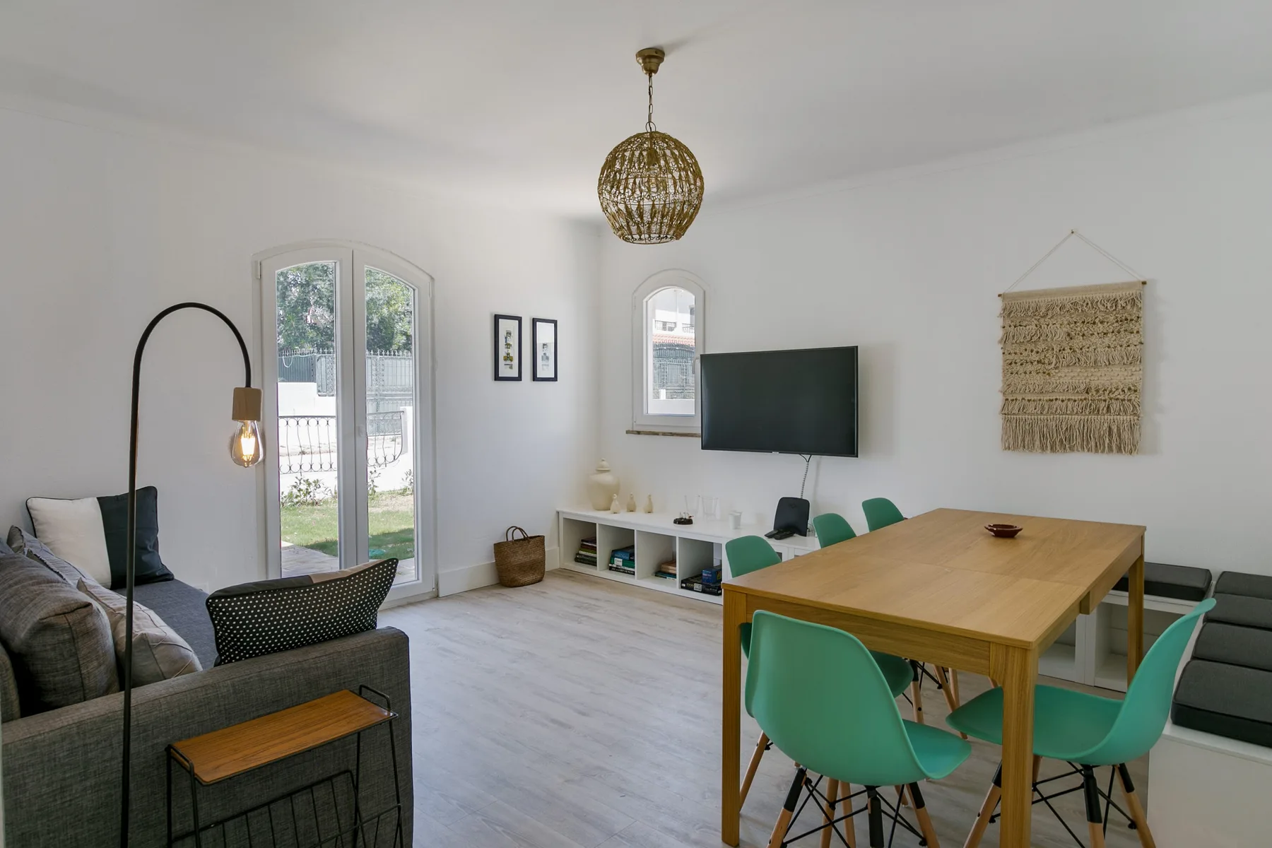 Una luminosa sala de estar y comedor con una mesa de madera y un televisor.