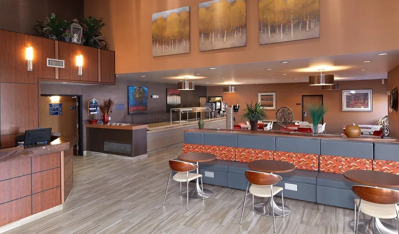 Vestíbulo del hotel con mesas, sillas y mostrador de recepción.