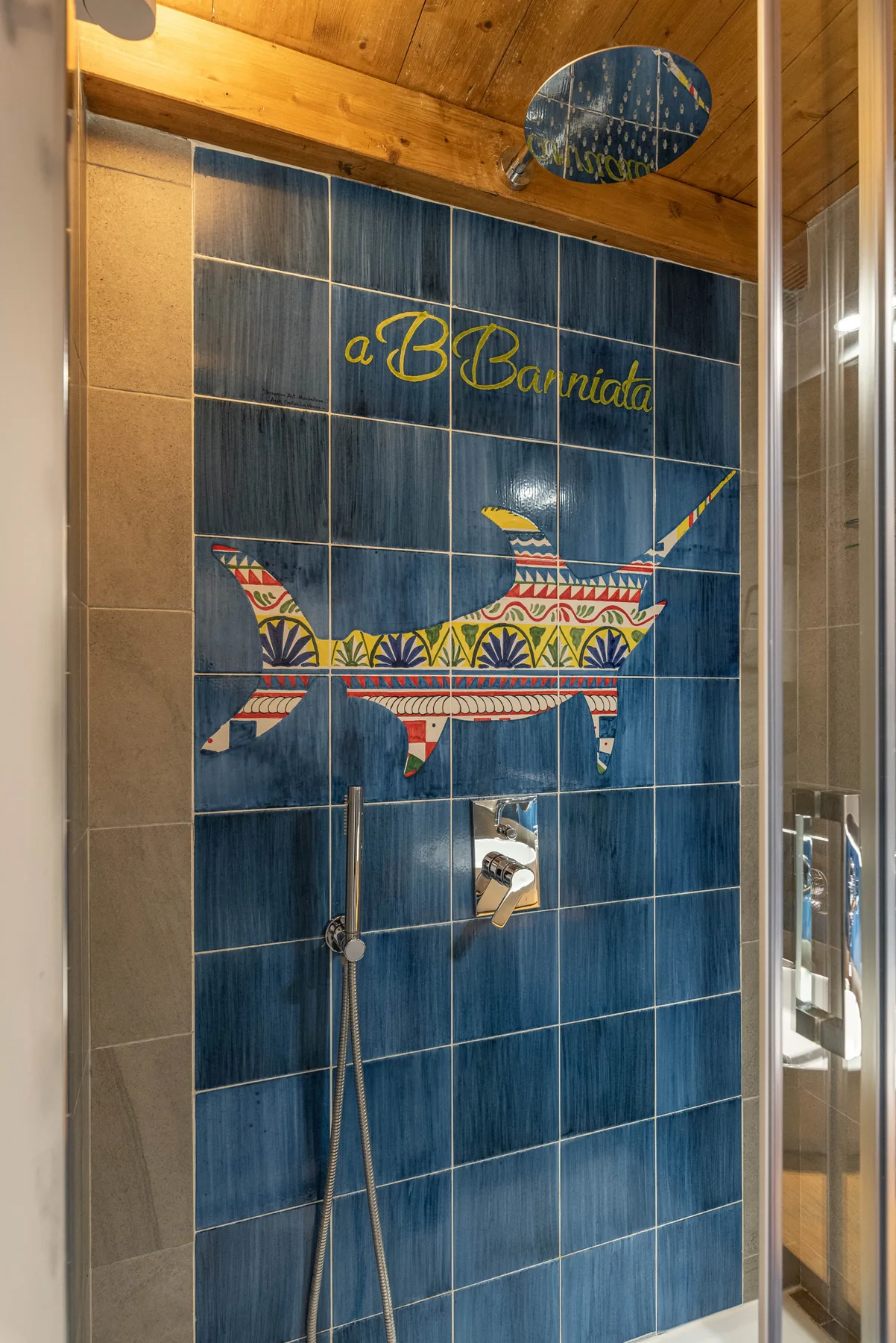 A tiled shower wall features a colorful airplane design beneath a wooden ceiling.
