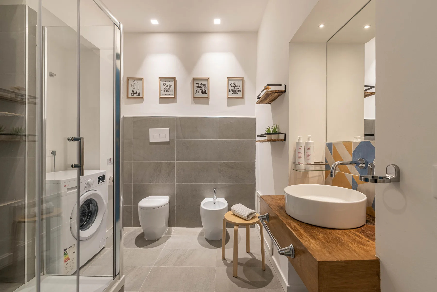 A bright bathroom with a shower, washing machine, and freestanding tub.