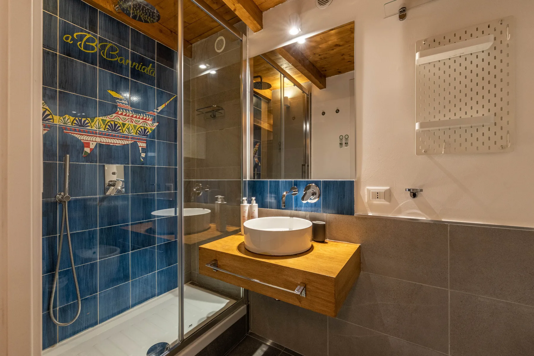 A bathroom with a glass shower and a white sink on a wooden vanity.