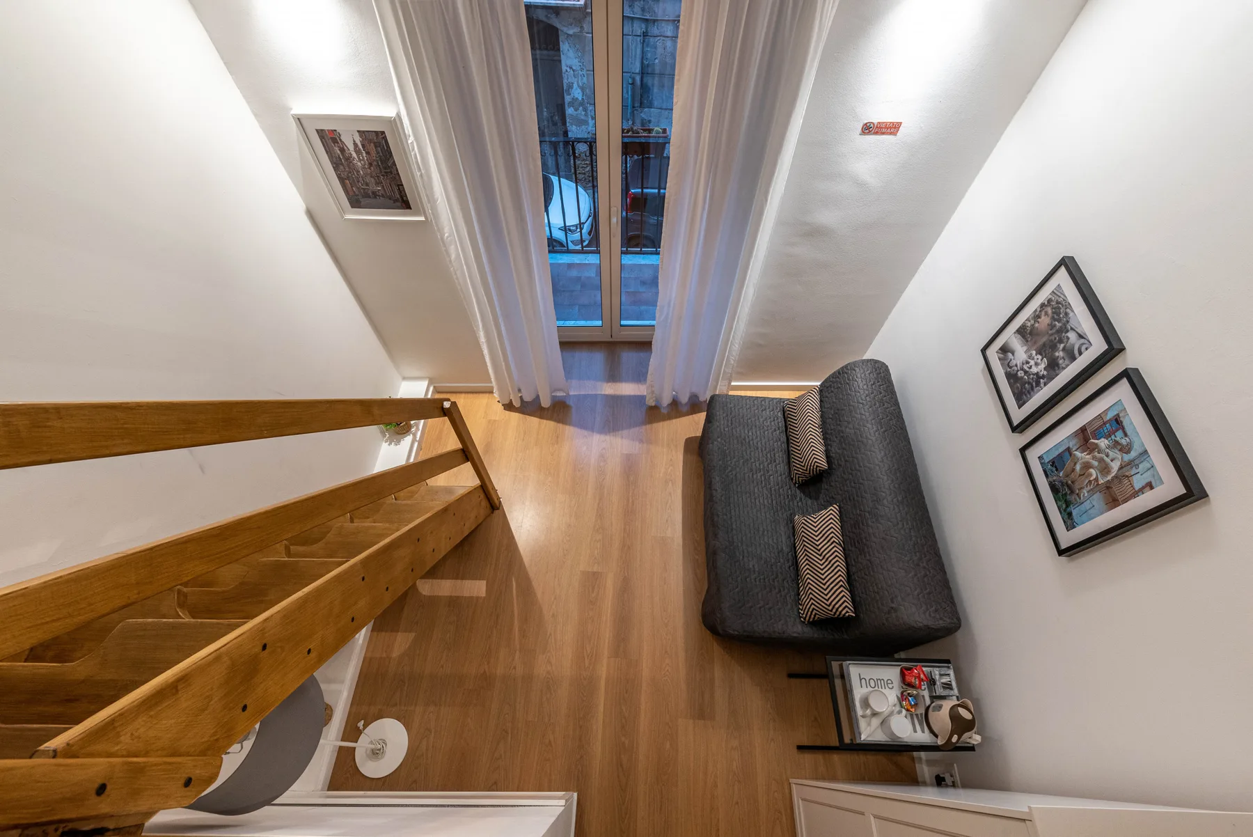 A narrow living area with a sofa beside a tall curtained window.