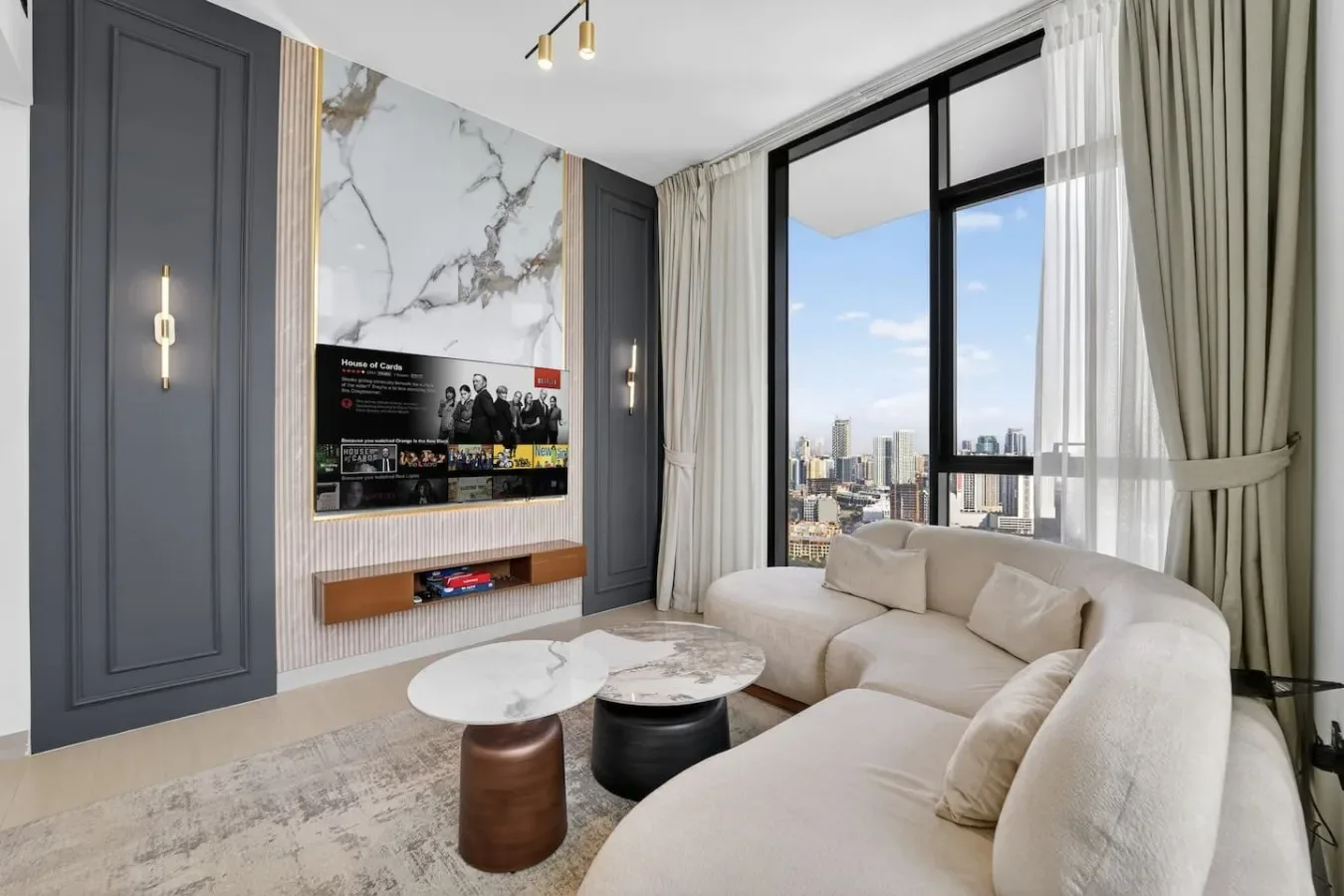 A bright living room with curved seating and large windows overlooking the city.