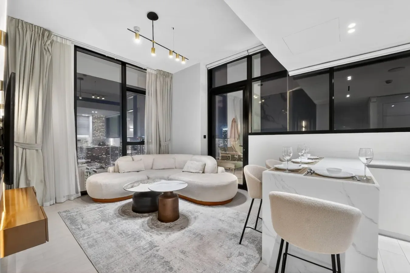 A bright living and dining area features curved seating beside a set dining table.