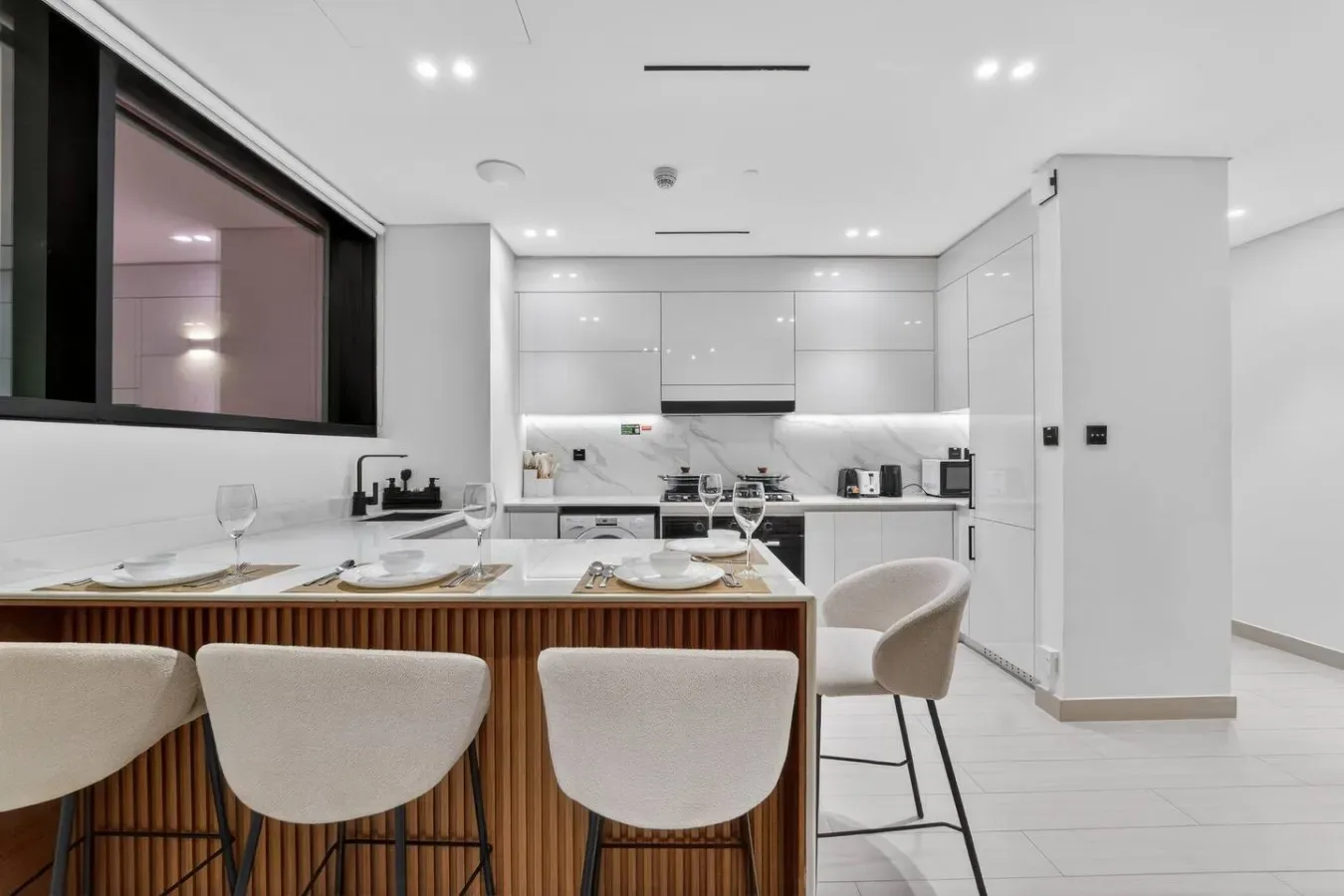 A modern kitchen with a dining island and white cabinetry.