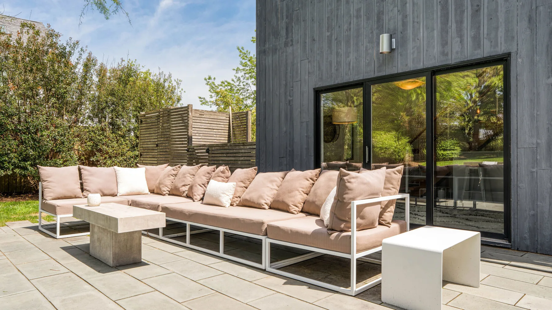 An outdoor patio with sectional seating beside large glass doors.