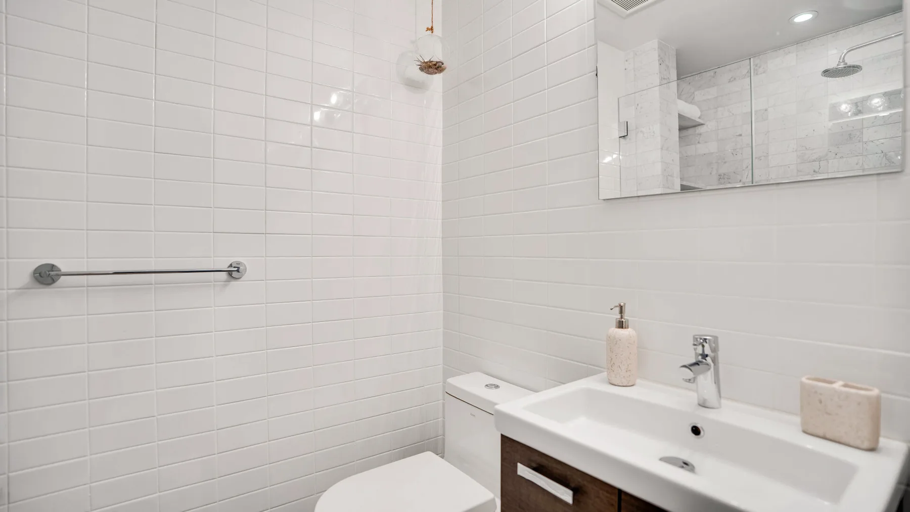 A tiled bathroom with a sink, mirror, and shower area.