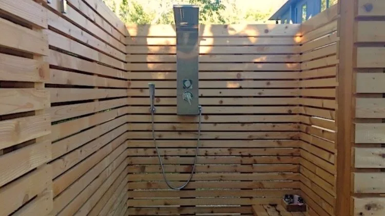 An outdoor shower area enclosed by horizontal wooden slats.