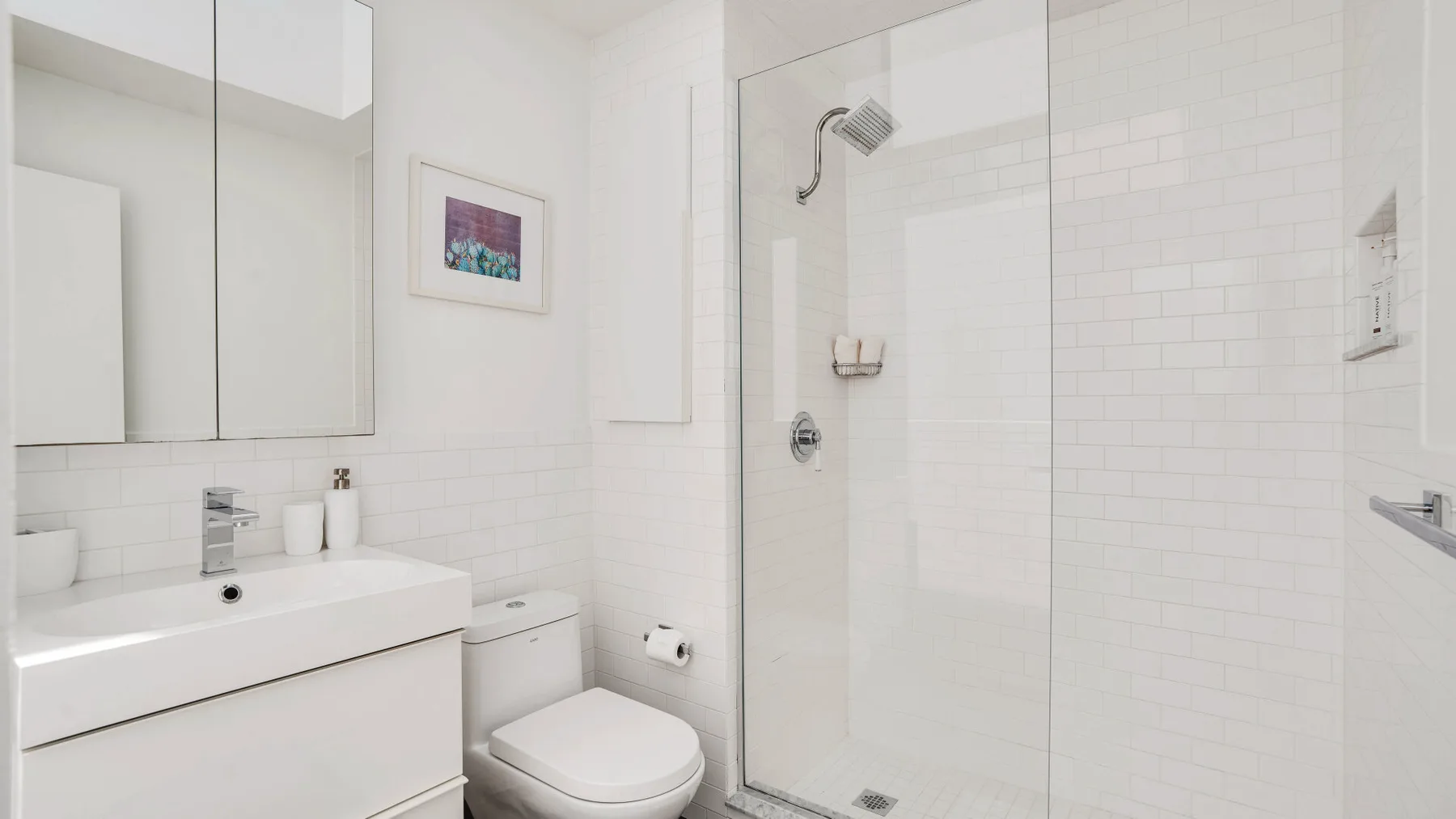 A bright bathroom with a glass shower and white vanity.