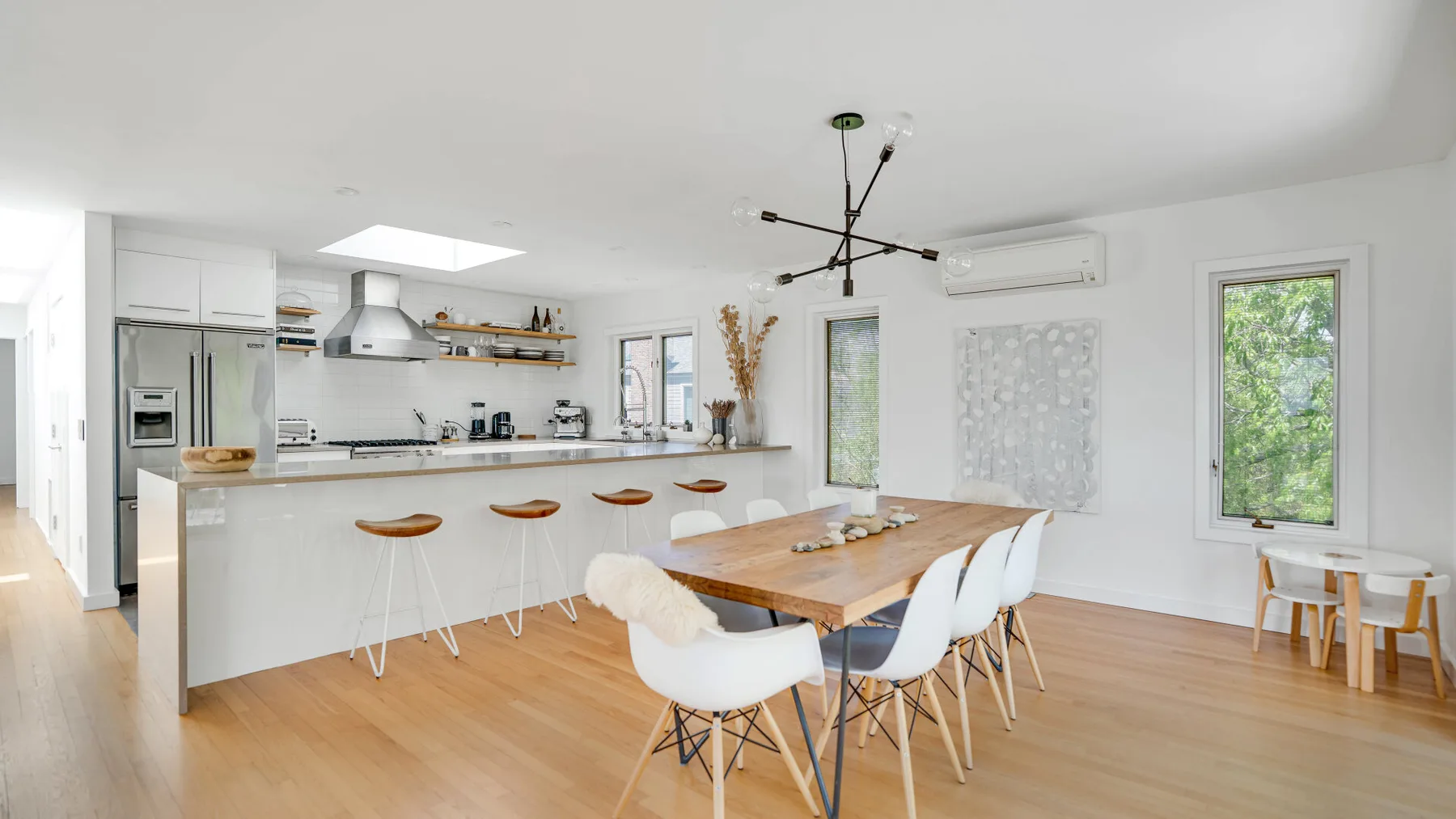 A bright kitchen and dining area with a long island and a wooden dining table.