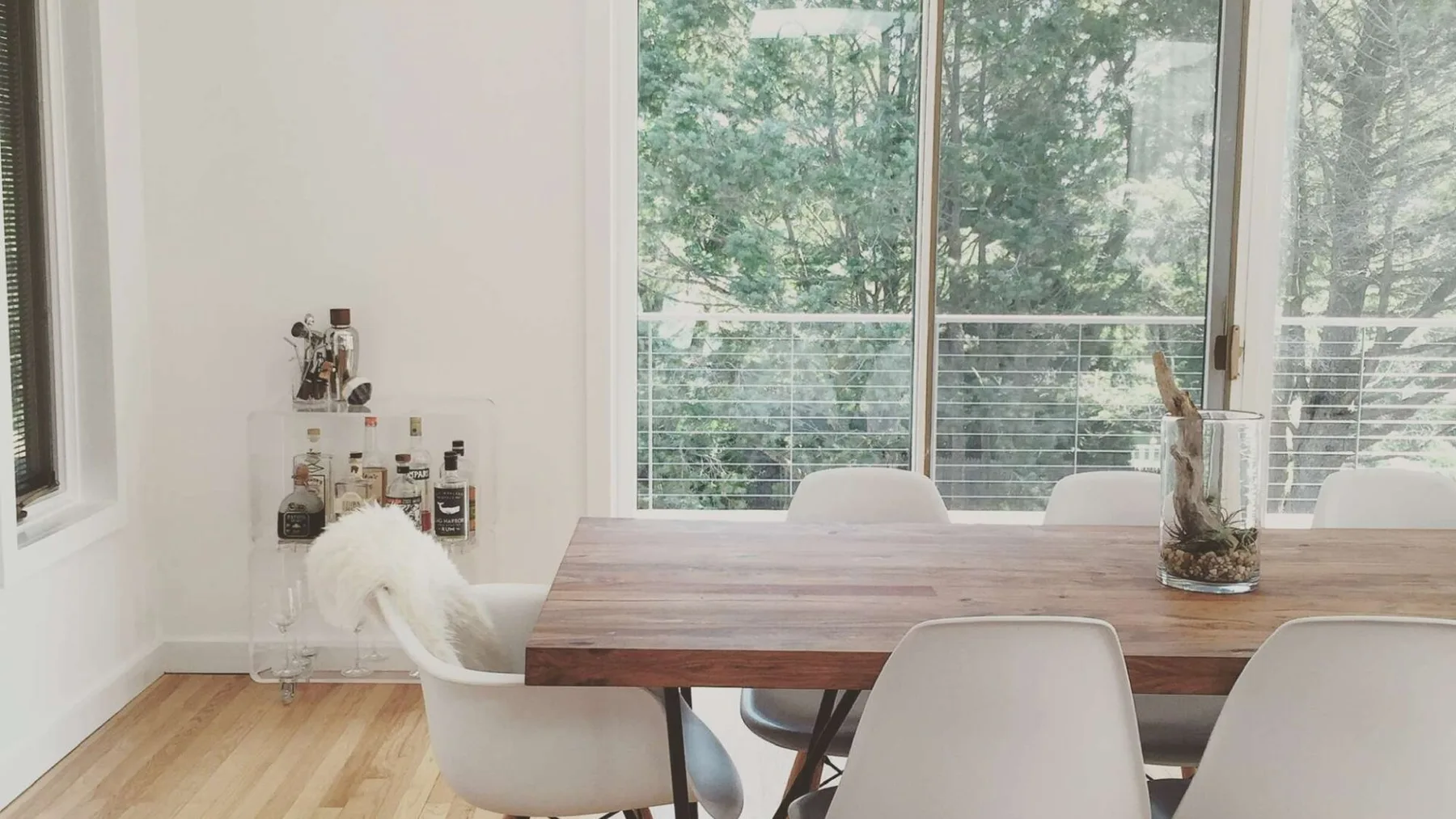 A dining area with a wooden table and large windows overlooking trees.