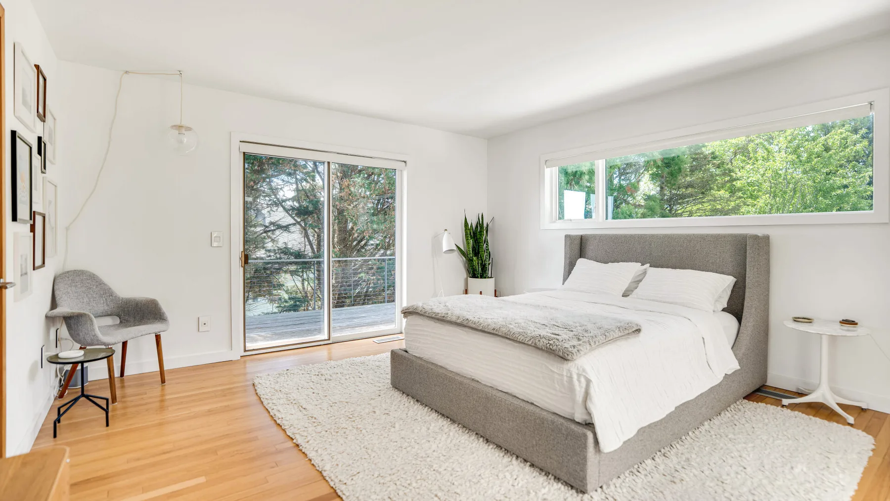 A bright bedroom with a large bed beside a sliding glass door.