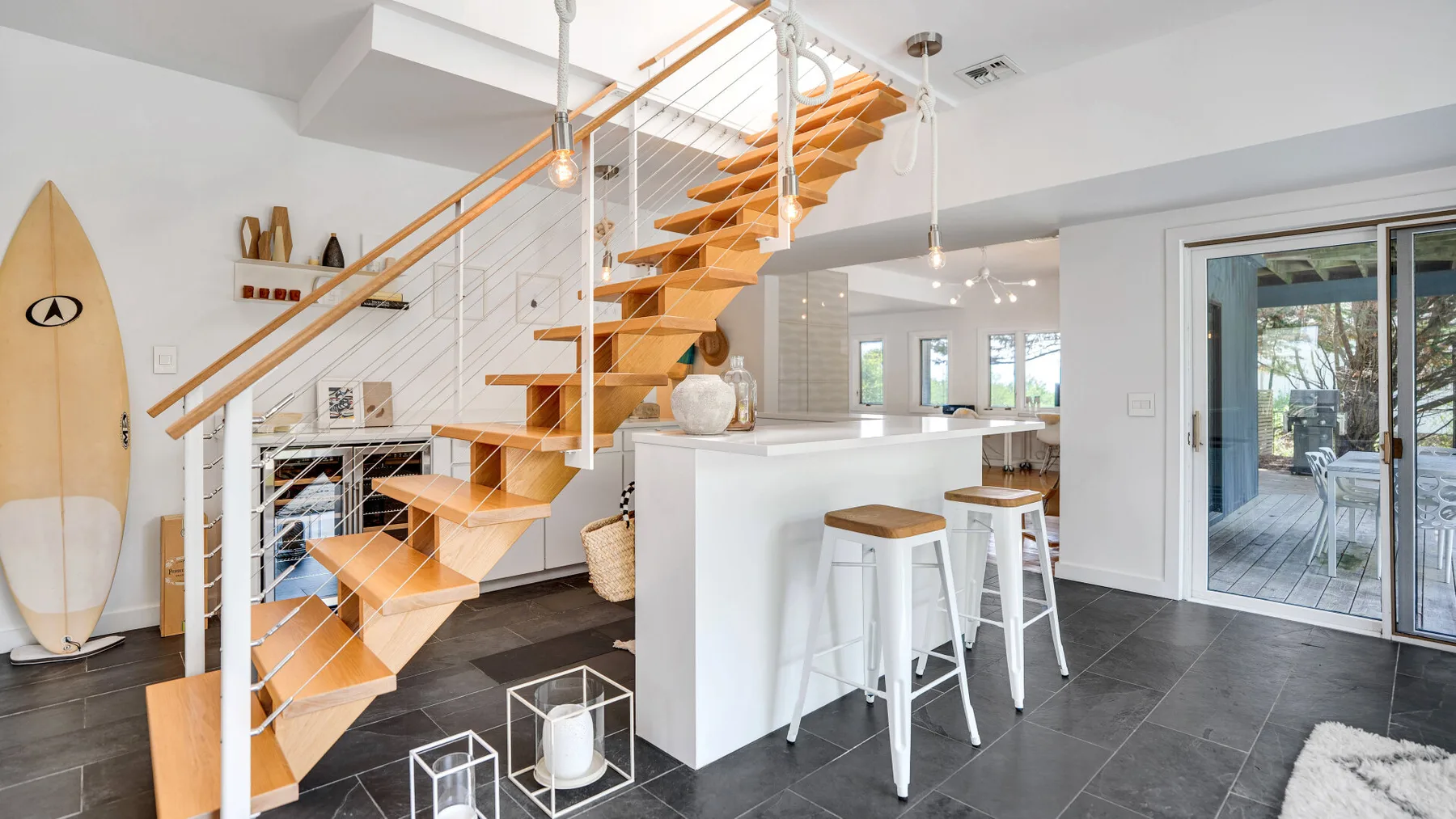 A modern open-plan kitchen and dining area features a wooden staircase and breakfast bar.