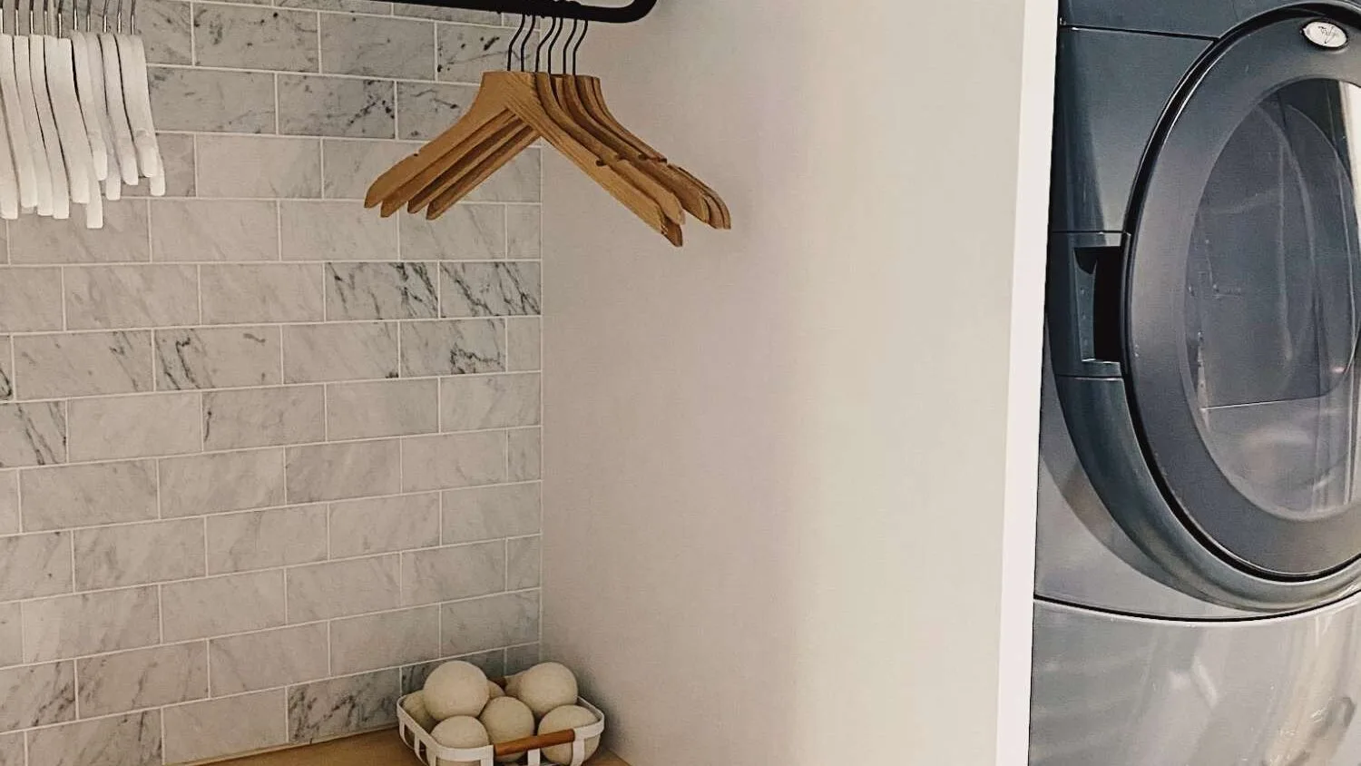 A laundry area with a front-loading washer and hanging clothes.