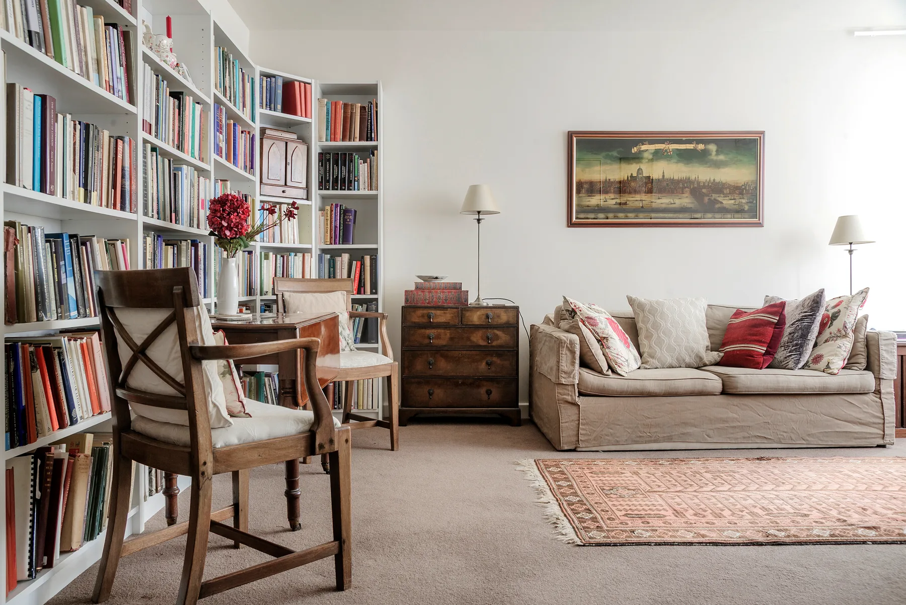 A living room with a bookcase, seating, and a patterned rug.