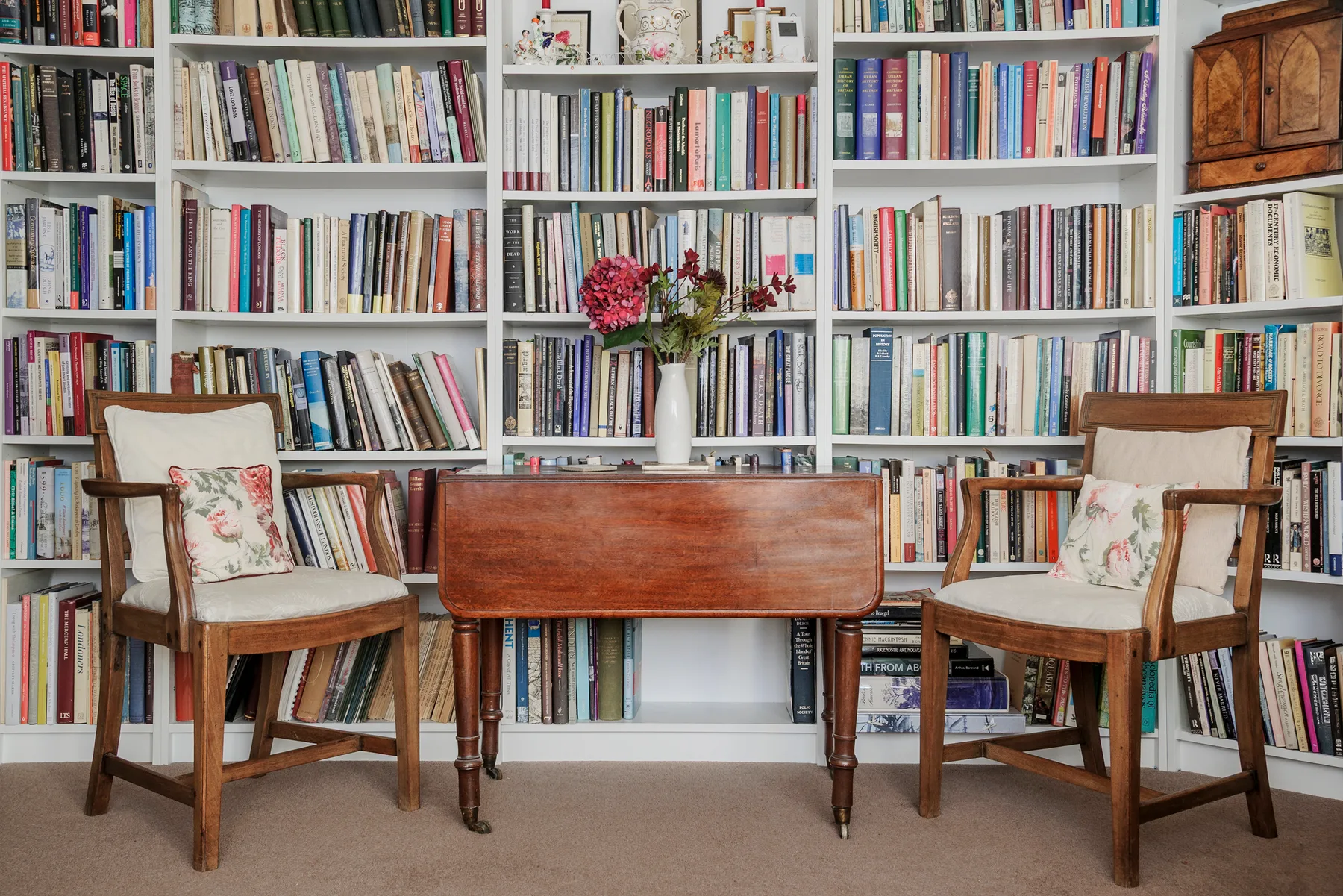 A study area with a wooden desk and seating in front of bookshelves.