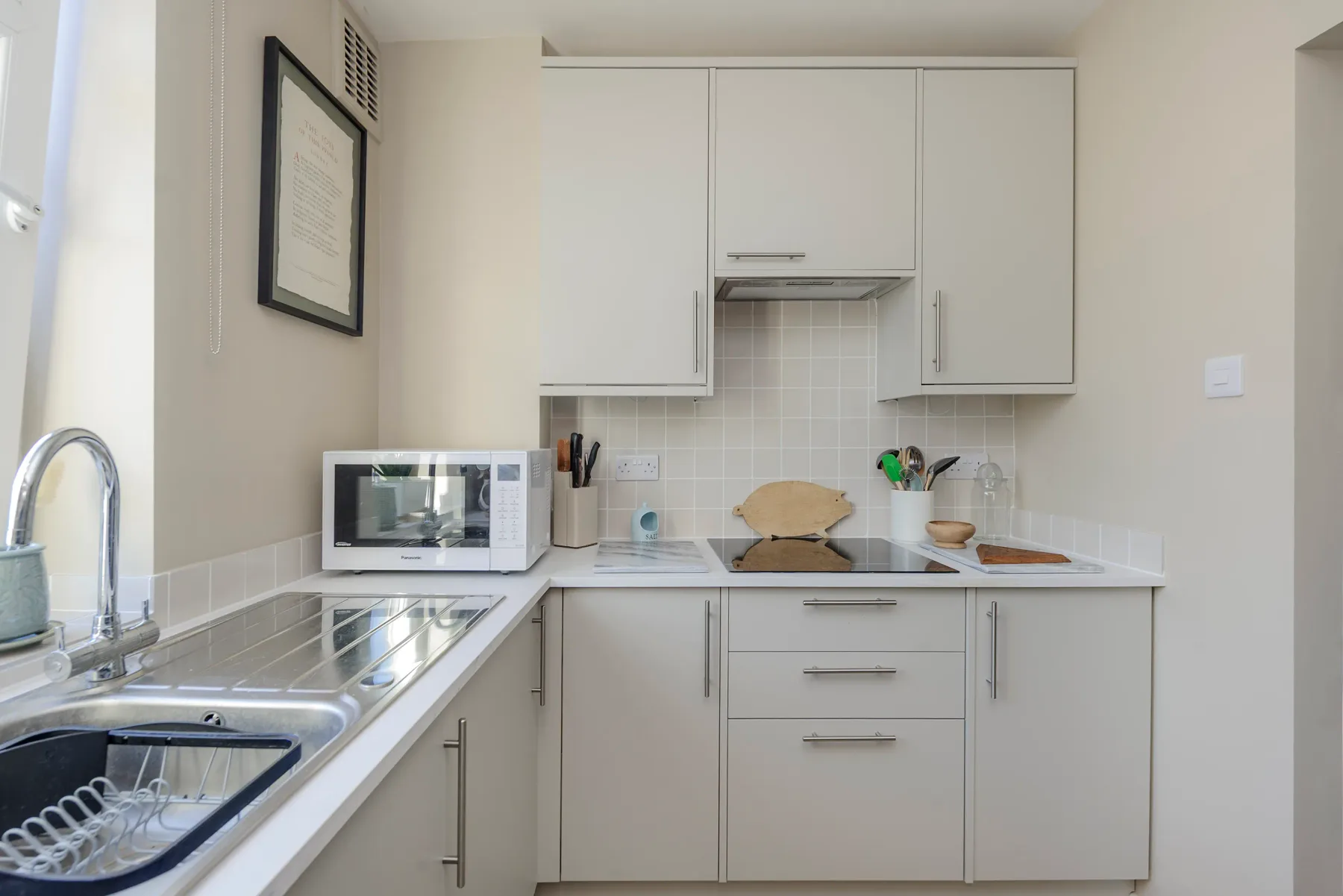 Una cocina luminosa con gabinetes blancos y un microondas sobre la encimera.