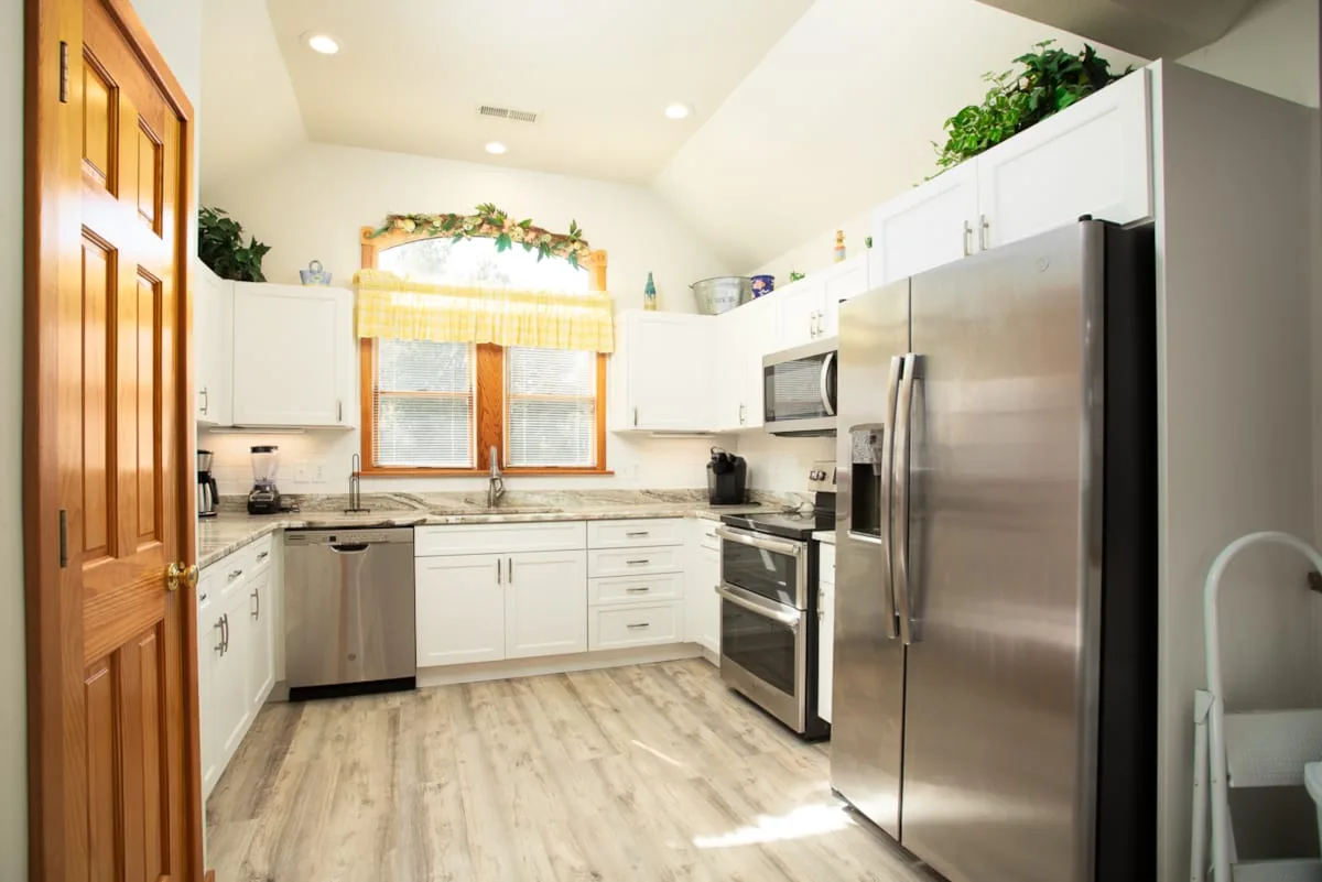 A bright kitchen with white cabinets and stainless steel appliances.