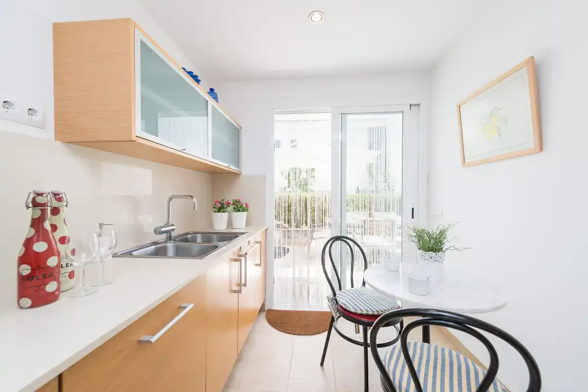 Una cocina luminosa con zona de comedor, encimera, mesa y sillas.