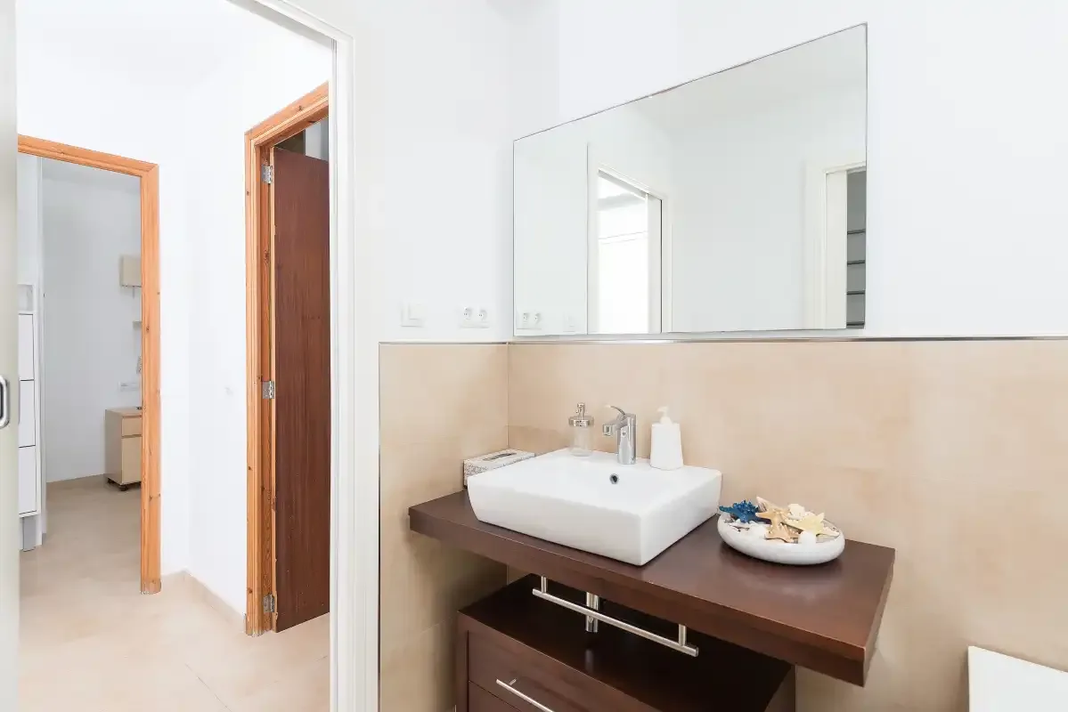 Un lavabo de baño con un fregadero blanco y un espejo grande en la pared.