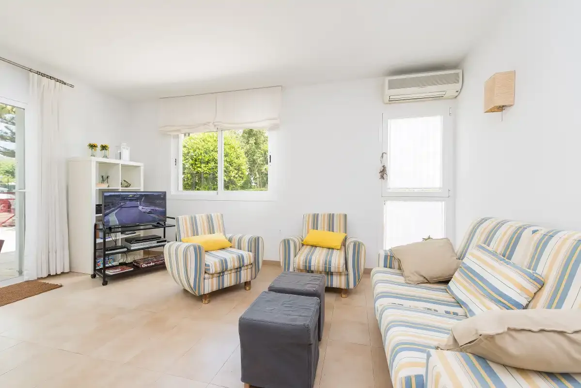 Una sala de estar luminosa con asientos a rayas y un televisor.