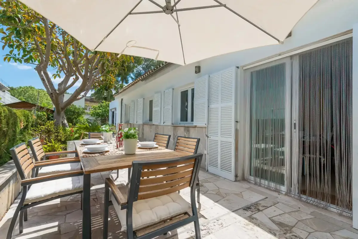 Comedor exterior con mesa y sillas junto a la casa.