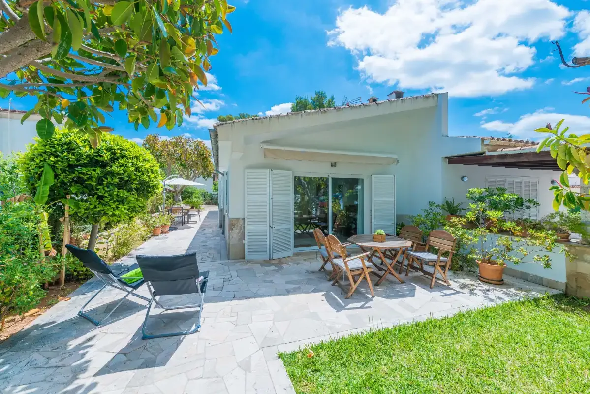 Un patio ajardinado con asientos al aire libre junto a una casa blanca.