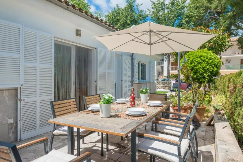 Una zona de comedor al aire libre con mesa y asientos bajo una sombrilla grande.