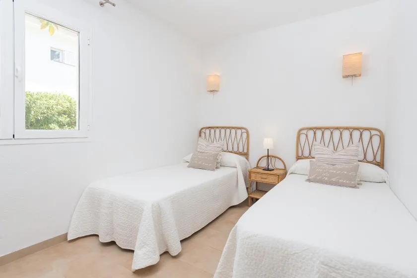 Dormitorio luminoso con dos camas y una ventana con vistas a la vegetación.