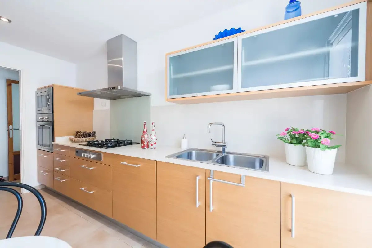 Una cocina moderna con gabinetes de madera, una placa de cocina y un fregadero.