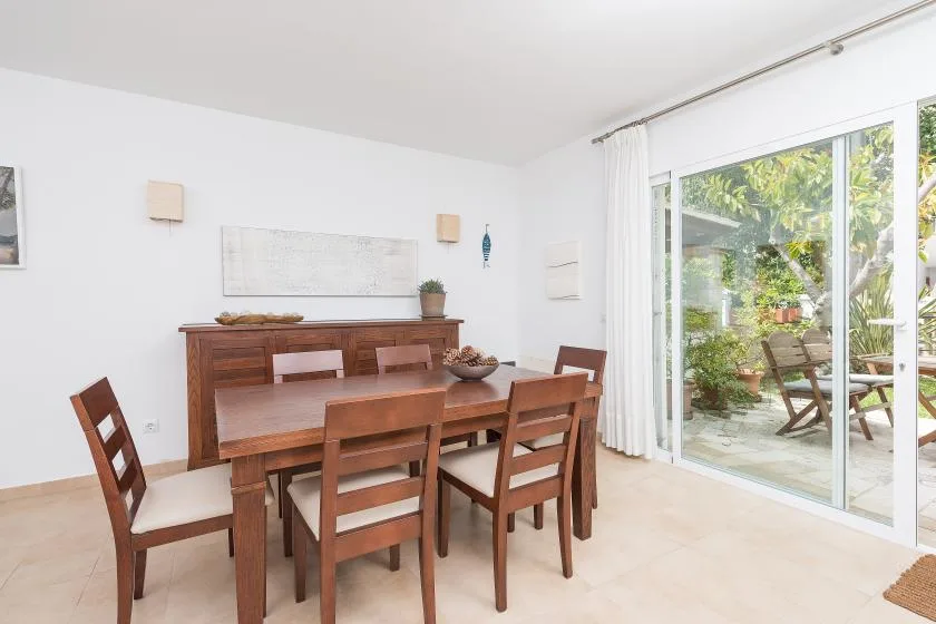 Comedor con una mesa de madera y sillas junto a una puerta acristalada al patio.
