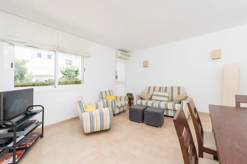 Una sala luminosa con asientos a rayas y un televisor junto a la ventana.