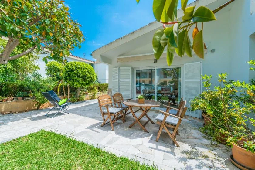 Un patio pavimentado con asientos al aire libre junto a una casa y un jardín.