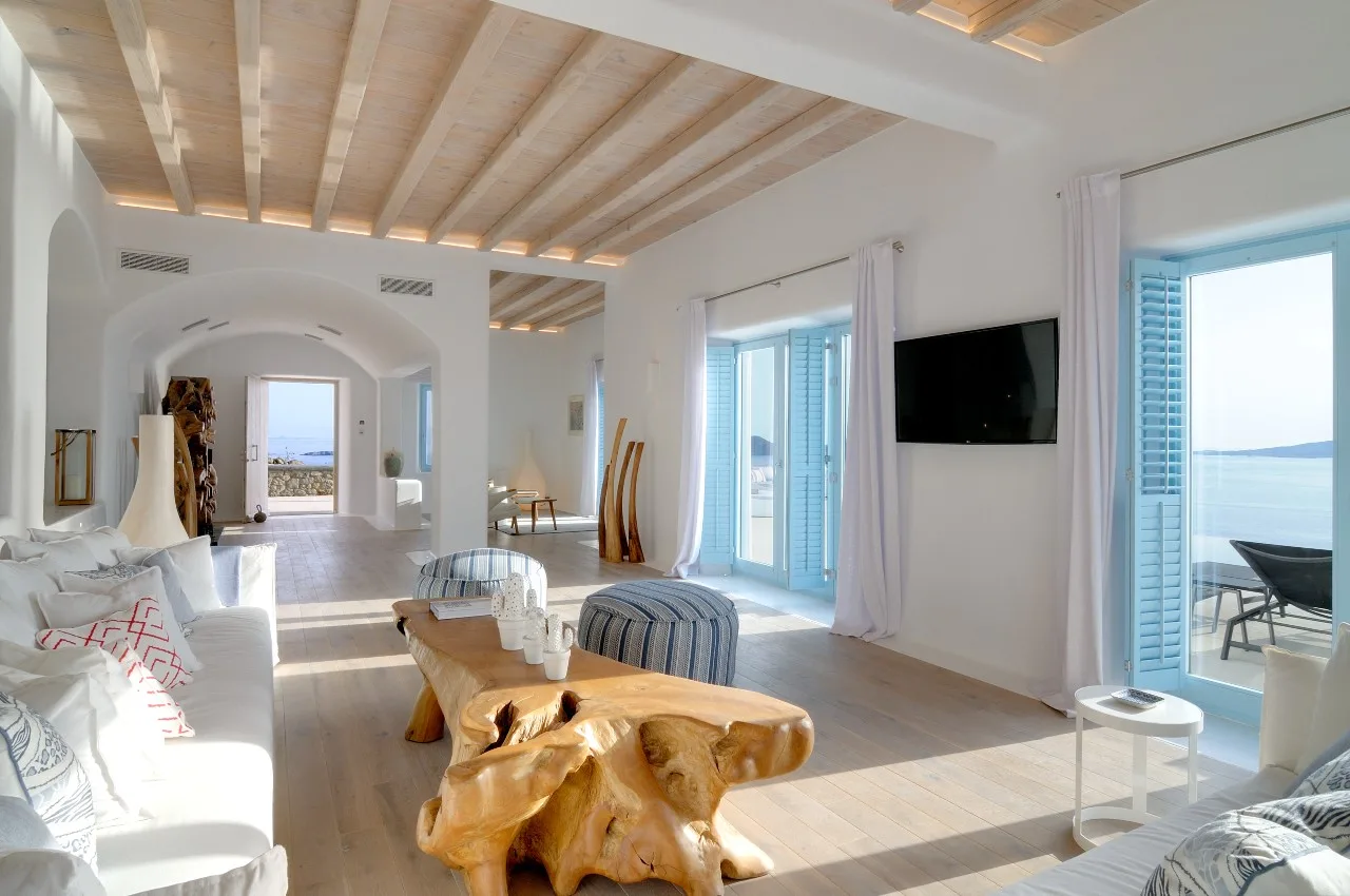 A bright living room has seating, a wooden coffee table, and wide glass doors.
