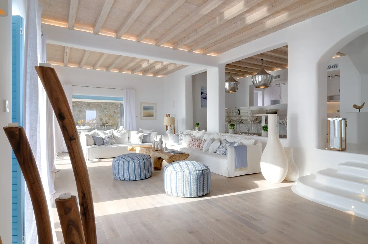Bright living room with white seating and a light wood-beamed ceiling.