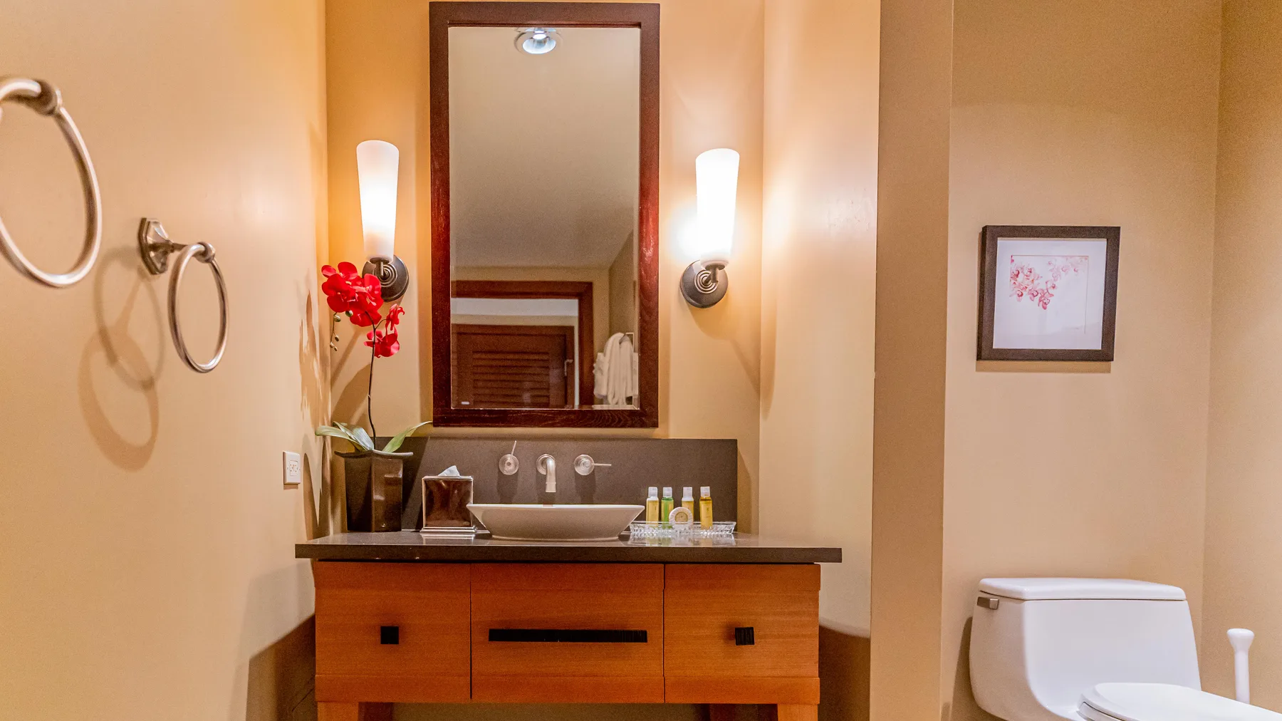 A bathroom vanity with a mirror, wall lights, and a toilet.