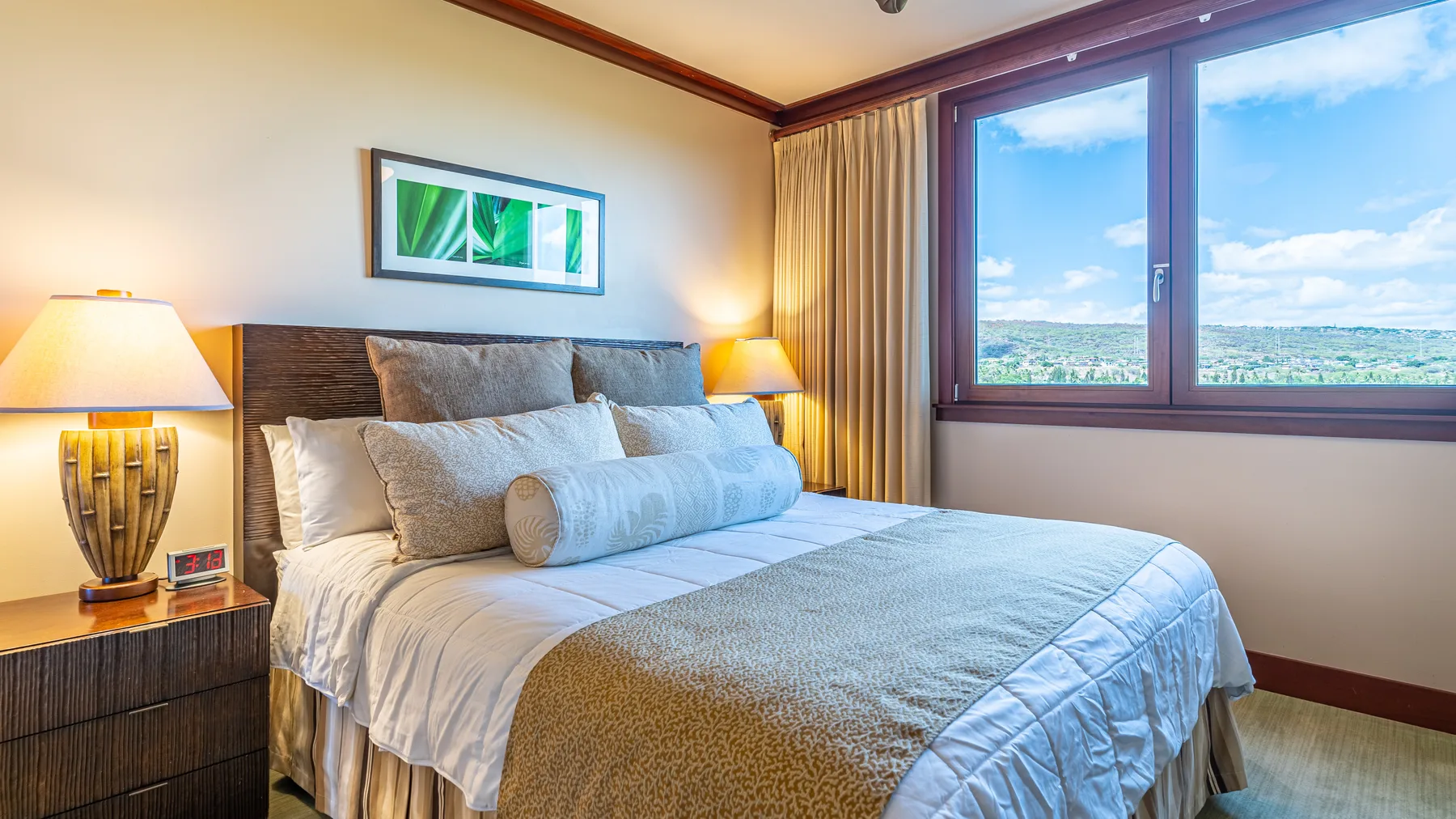 A bedroom with a neatly made bed beside a large window overlooking a green landscape.