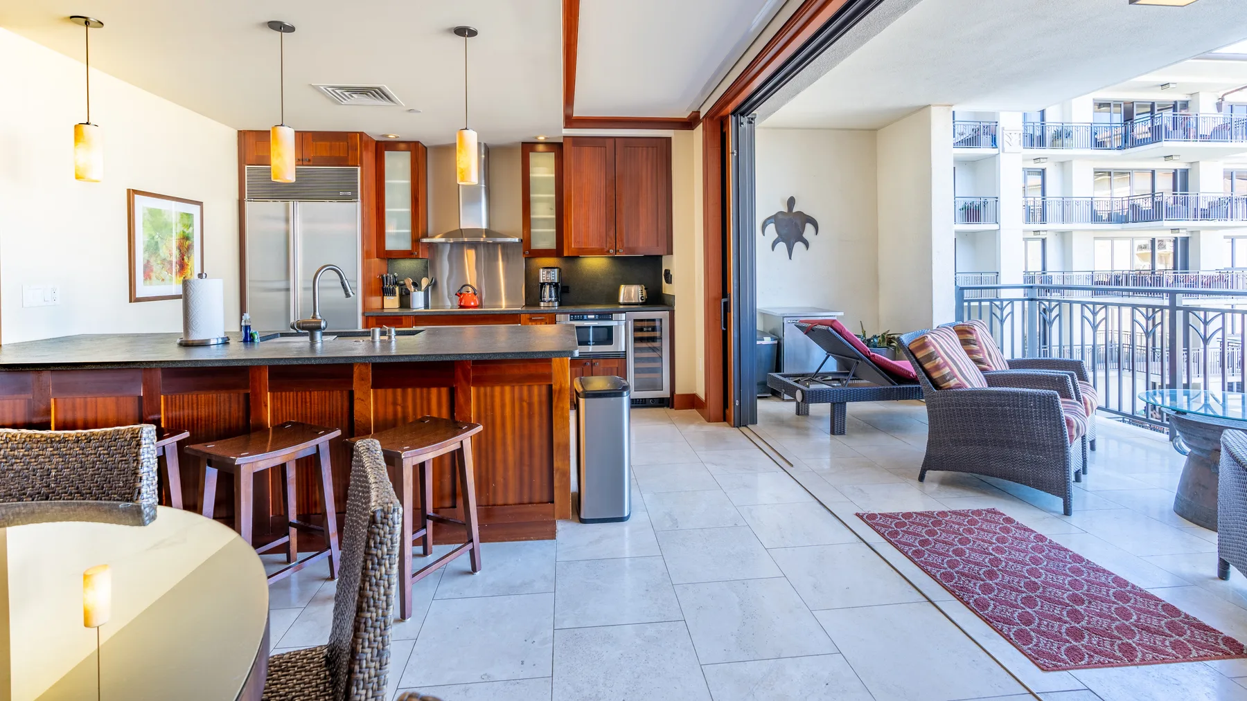 An open-plan kitchen and dining area leads to a balcony with seating.