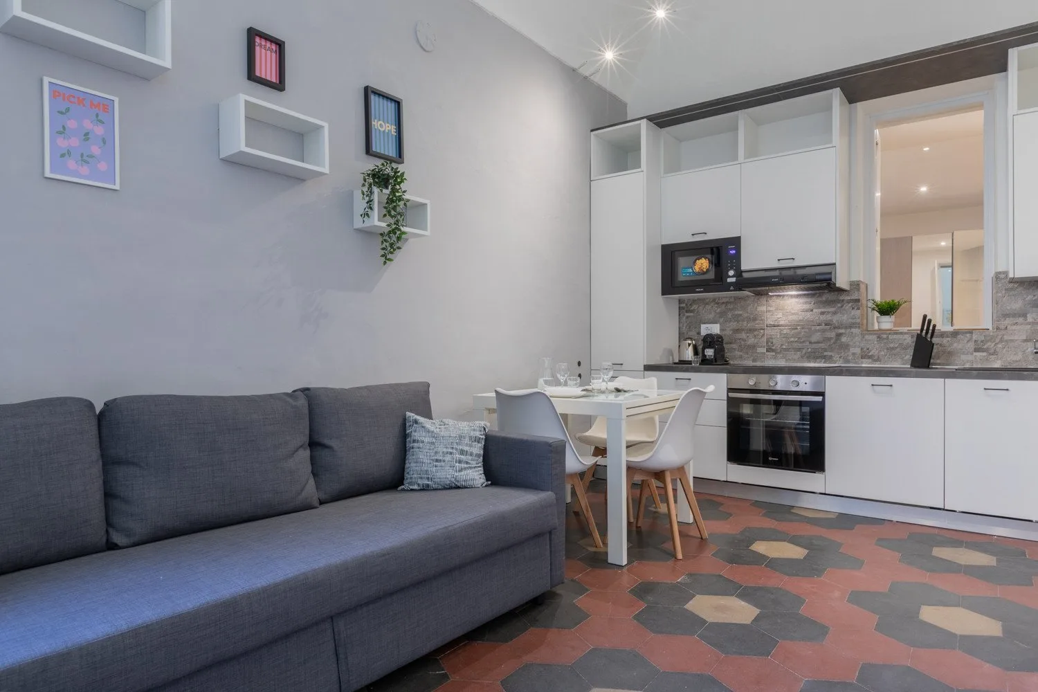 An open-plan living and dining area with a dark sofa and white kitchen.